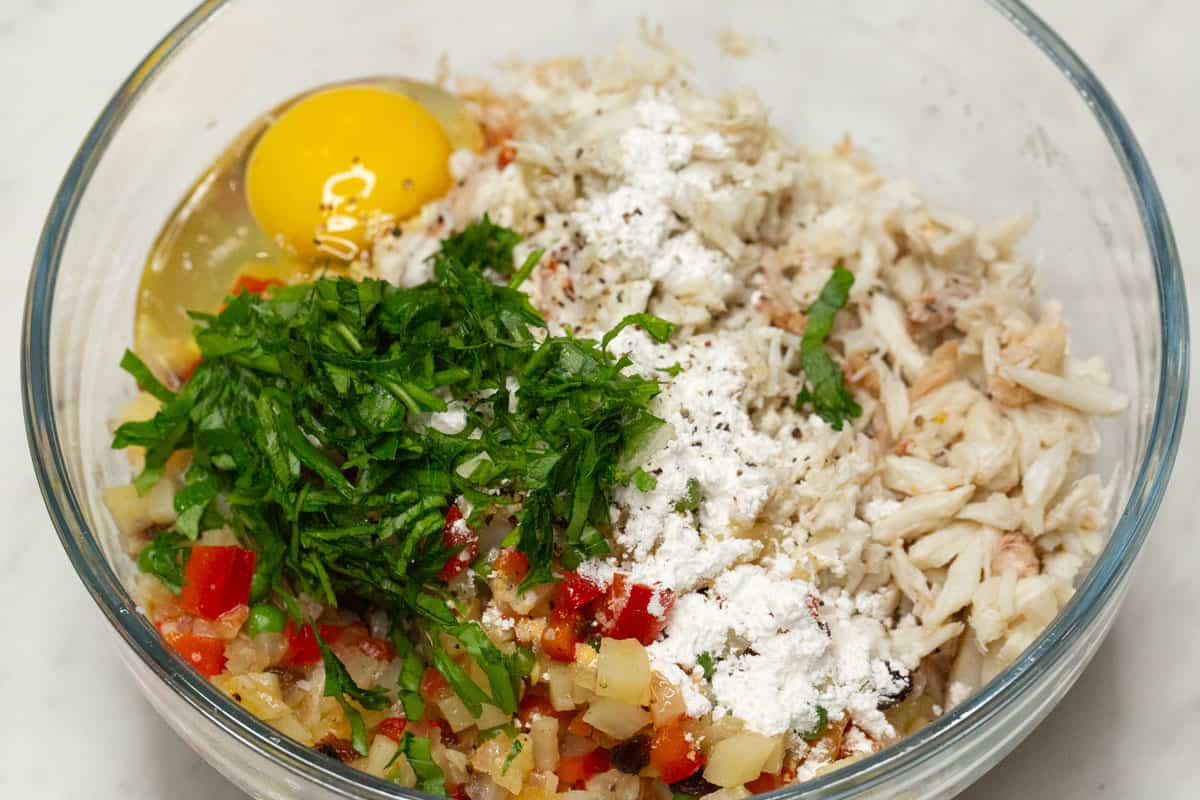 Crabmeat, sauteed vegetables, egg, and other ingredients in a bowl.