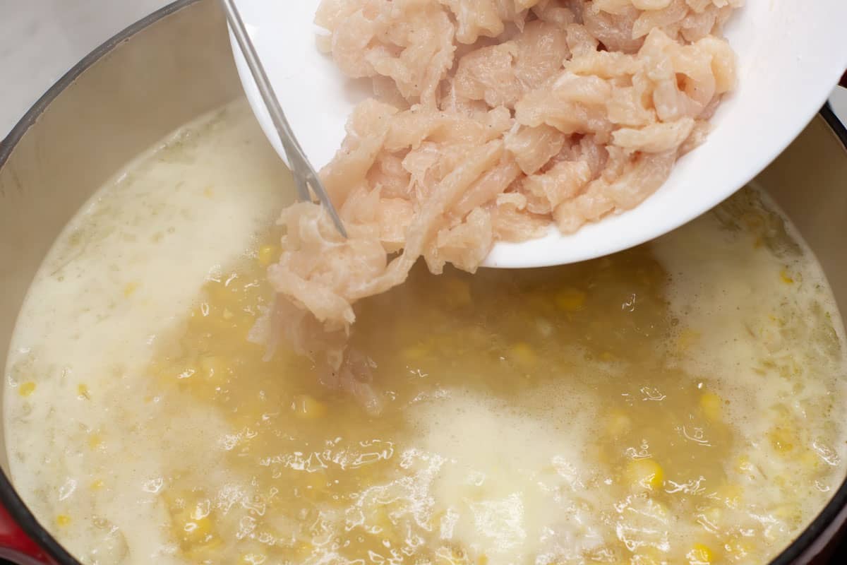 Adding the chicken pieces into the simmering broth.