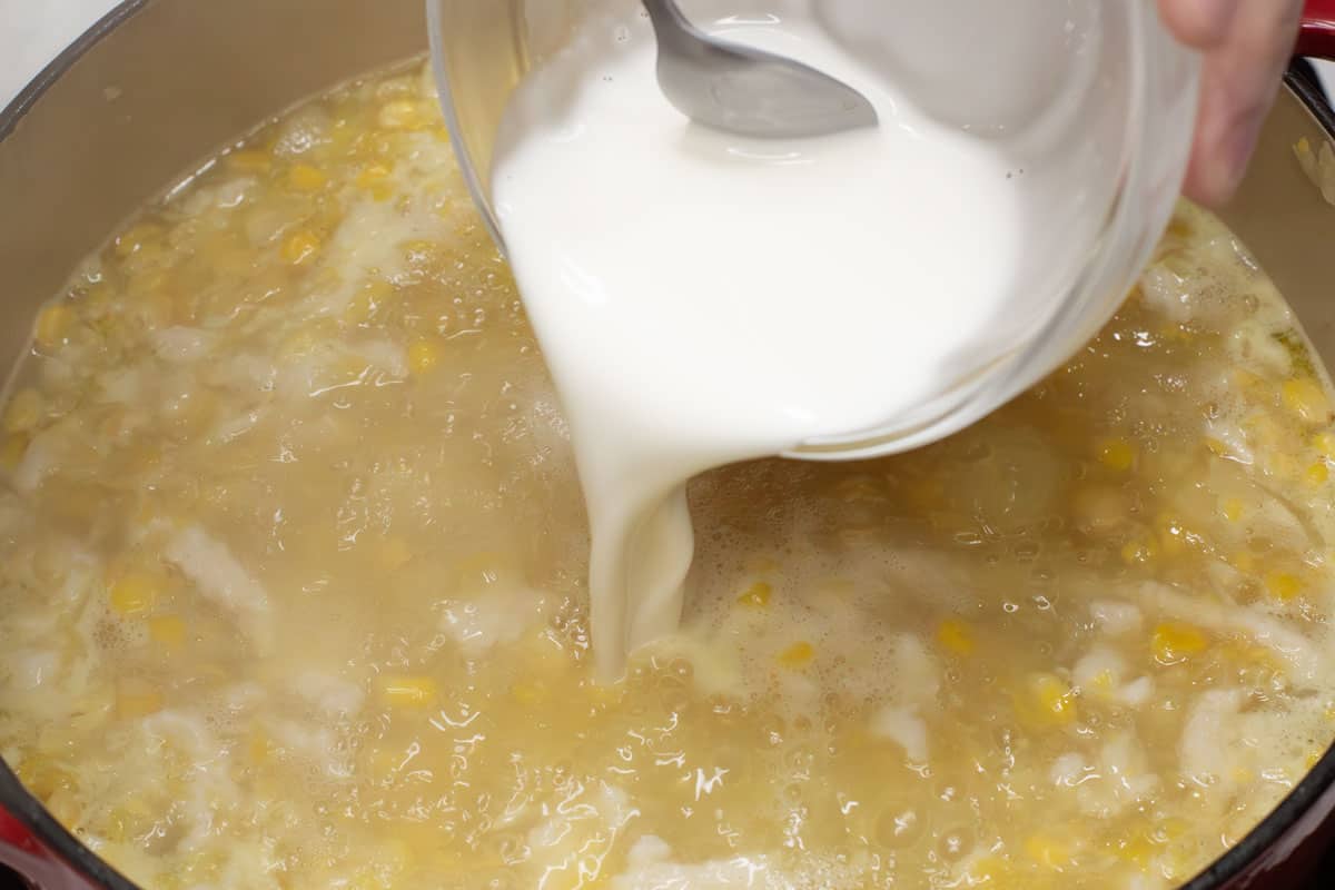Adding the cornstarch slurry to the mixture in the pot.
