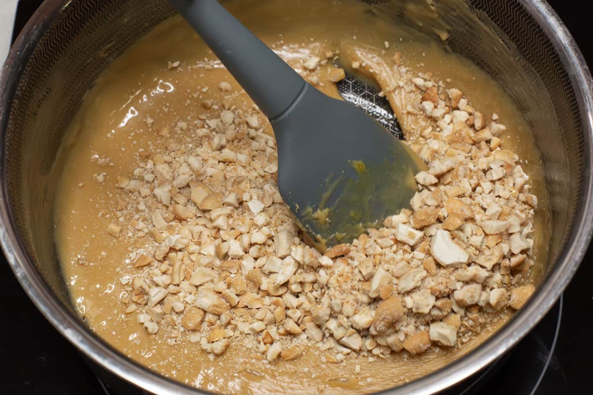 Yema candy mixture with chopped cashew nuts in a saucepan.