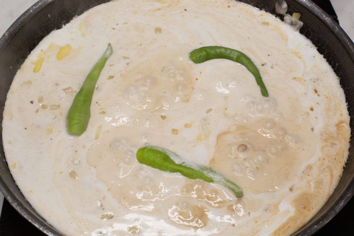 Coconut milk simmering in the pan with chilies.