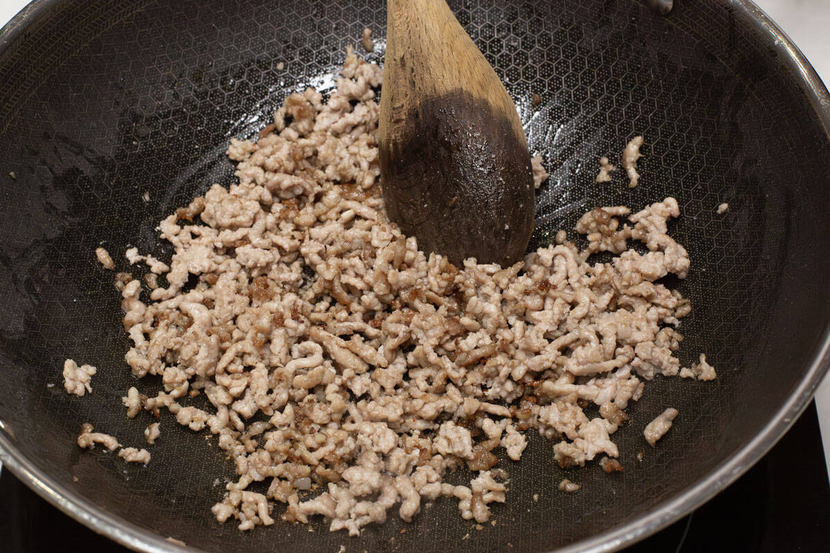 Browning the pork in a wok.