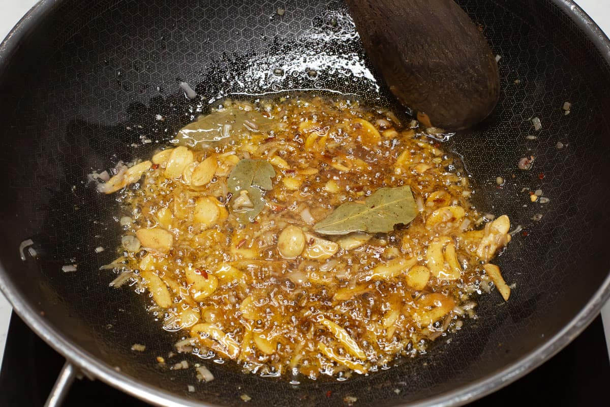 Sauteing garlic and shallot with spices in a wok.