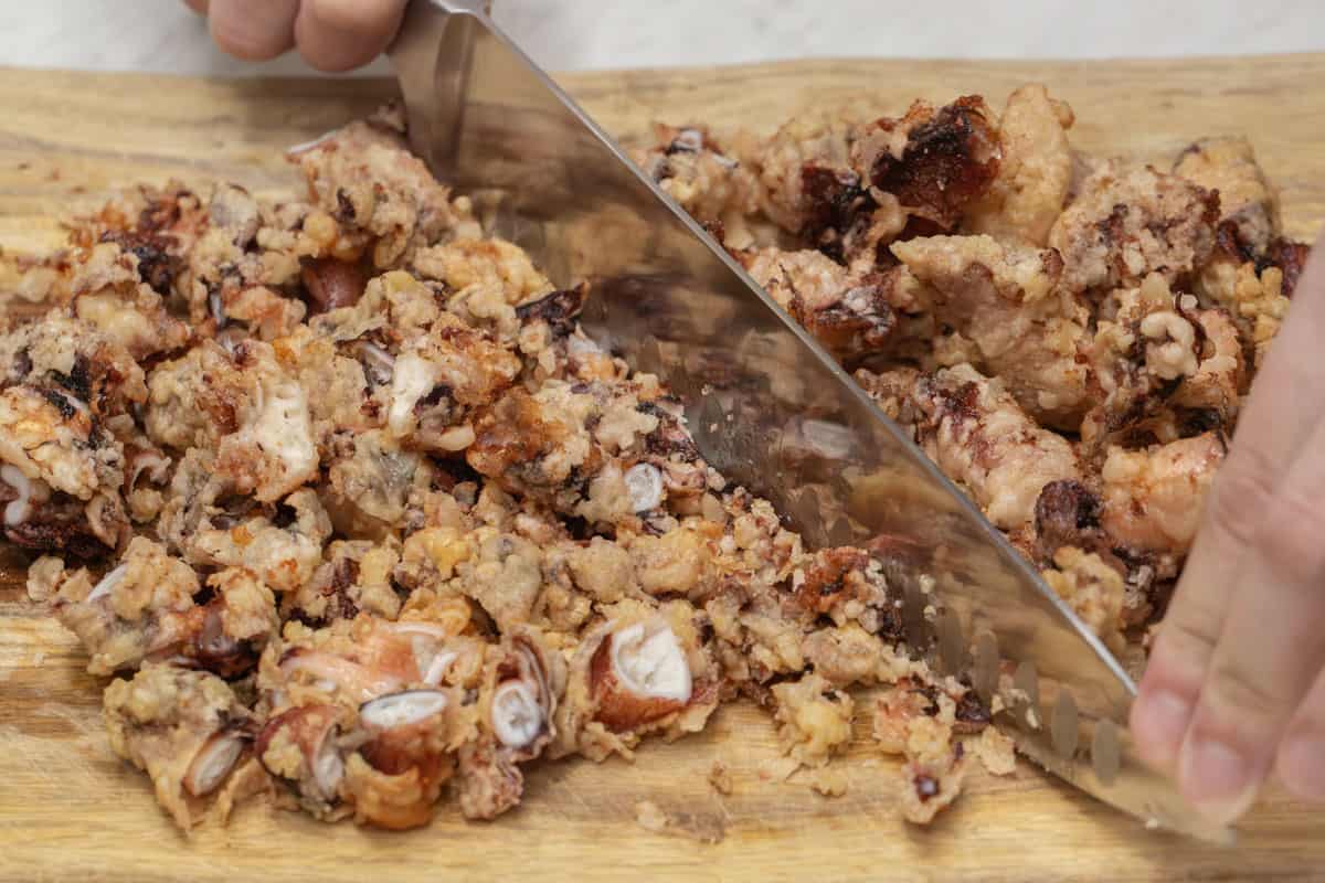 Chopping up the fried squid on a cutting board.