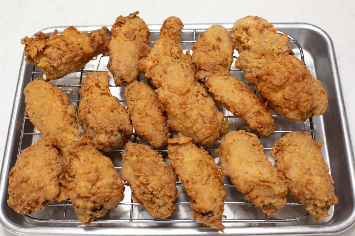 Fried chicken wings resting on a wire rack.