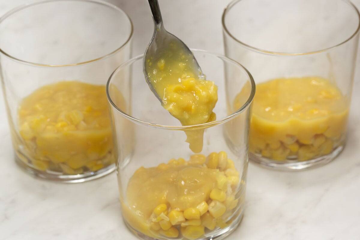 Adding cream-style corn to a glass.