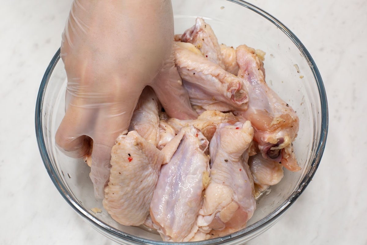 Massaging chicken pieces with hand.
