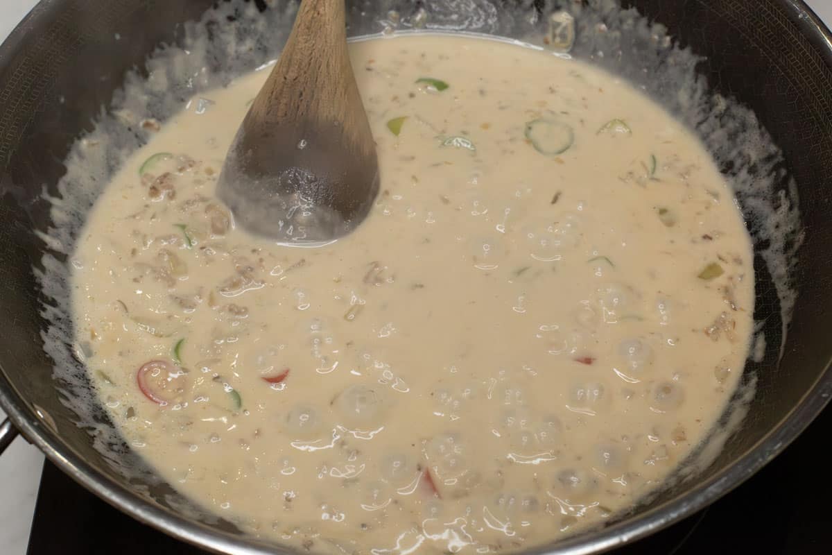 Coconut milk simmering in a wok.