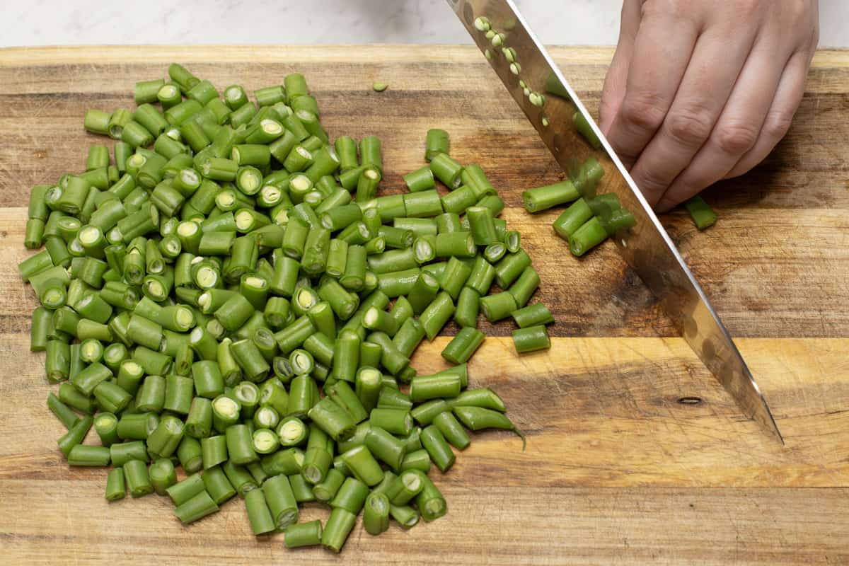 Cutting the green beans into ½-inch pieces.