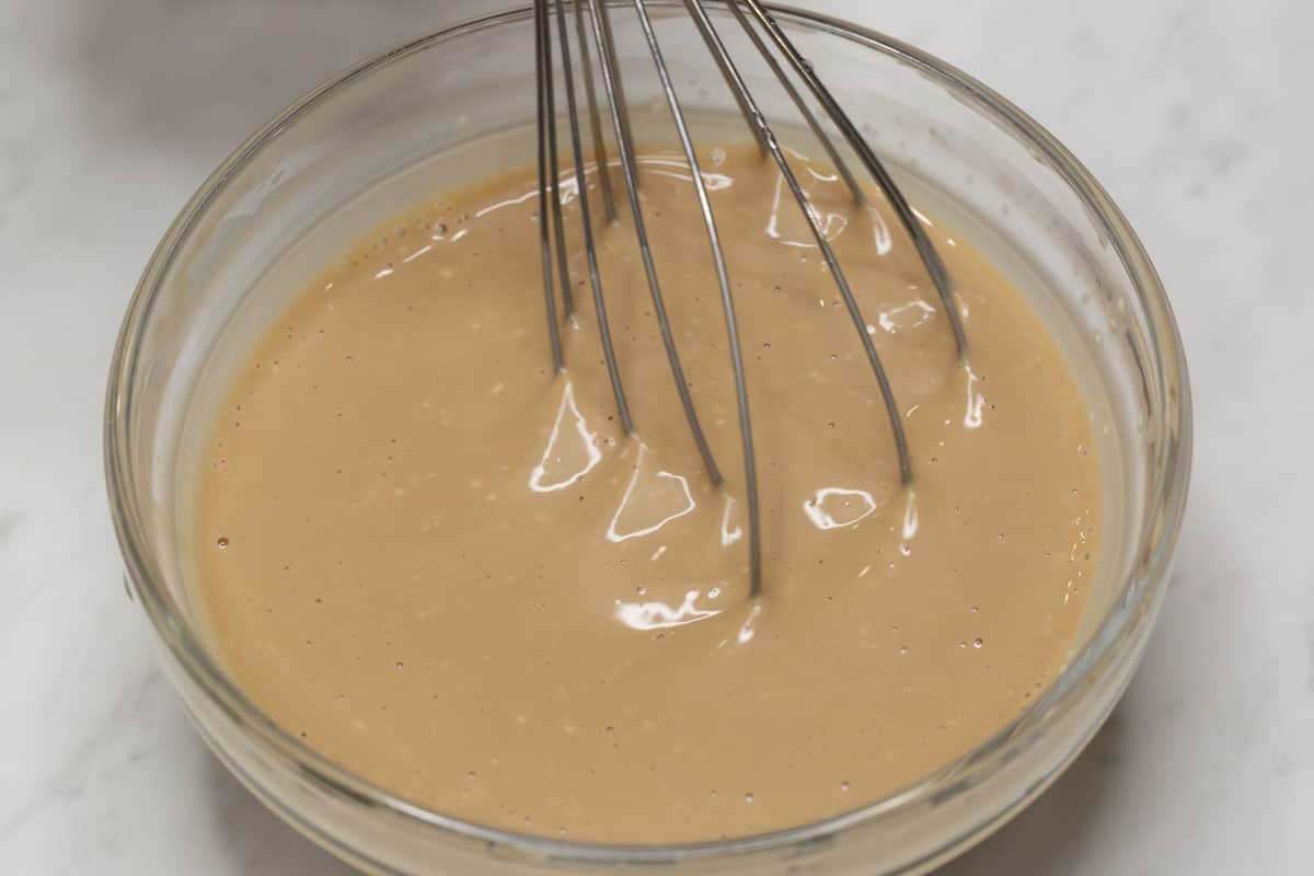 Mixing the sauce in a bowl using a whisk.