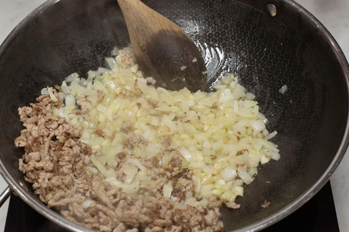 Sauteing the aromatics and pork in a wok.