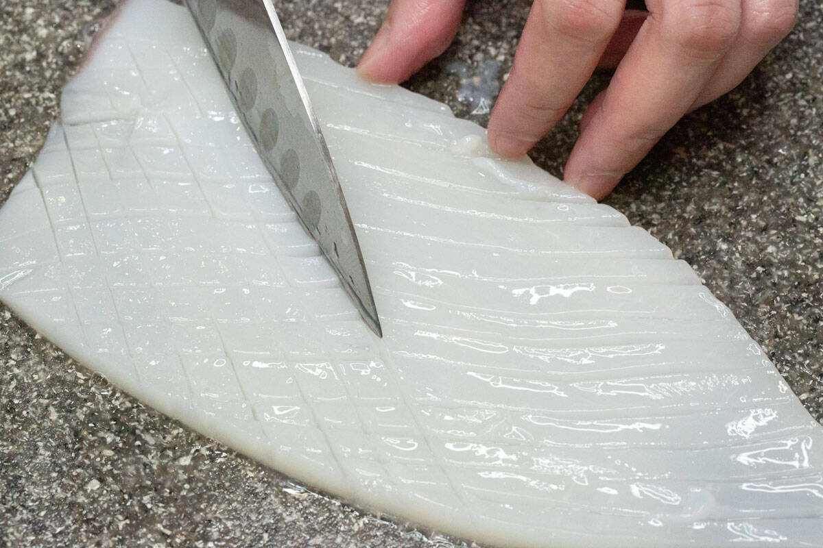 Scoring the inside of the squid body in a crisscross pattern.