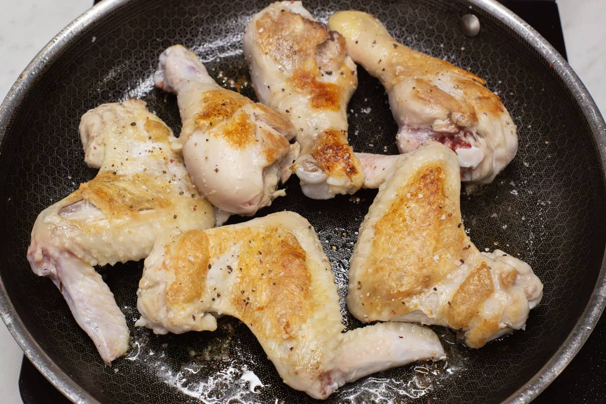 Searing the chicken in a skillet.