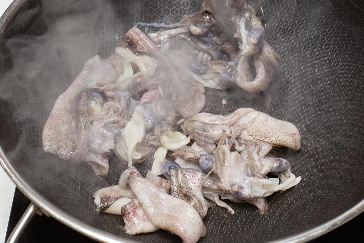 Searing the squid in a wok over high heat.