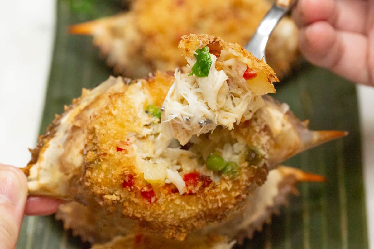 Crab relleno on a fork while holding the stuffed shell.