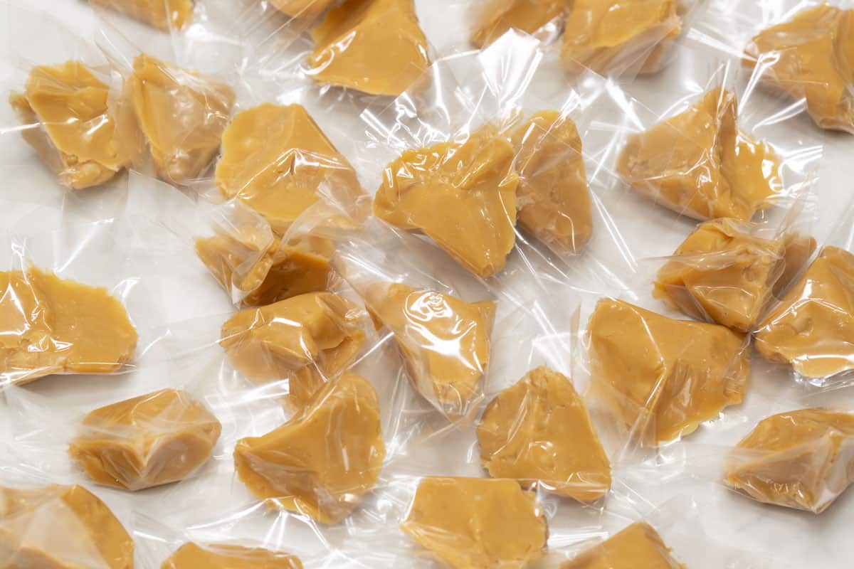 Yema candies wrapped in clear cellophane on a countertop.