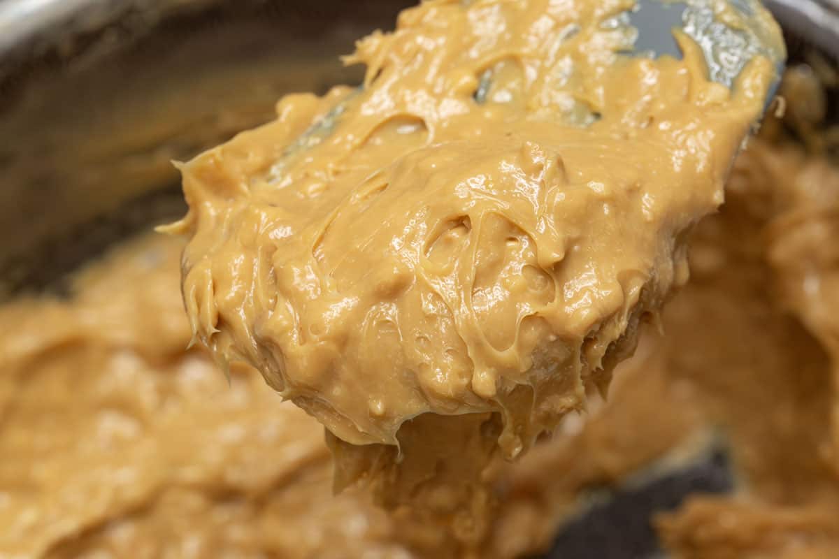 Lifting a portion of the yema candy from the saucepan using a spatula.
