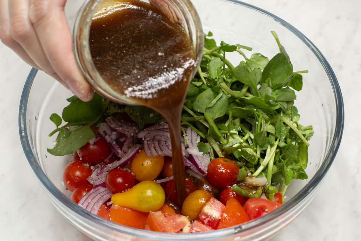Pouring the dressing over the vegetables in a bowl