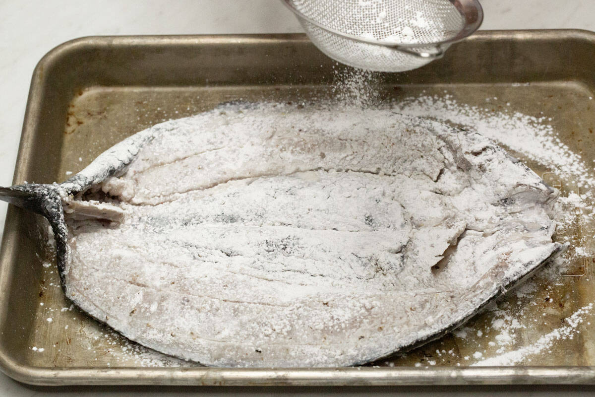 Coating the milkfish with flour.
