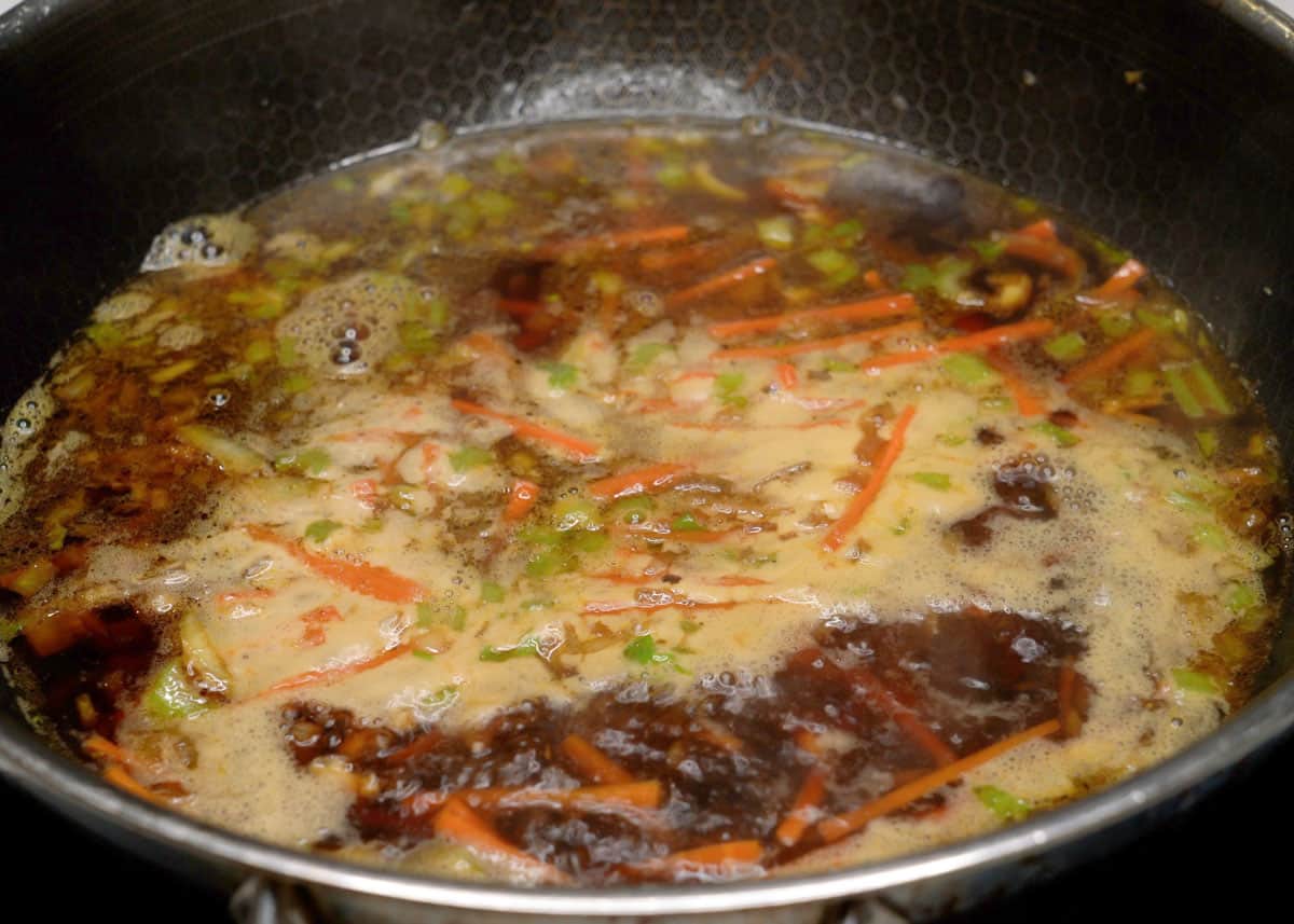 Pancit canton sauce boiling in a wok.