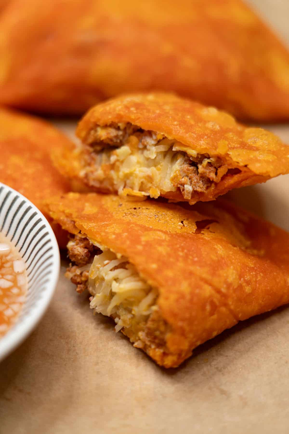 Ilocos Empanada (Vigan-Style) cut in half with vinegar dipping sauce on the side.