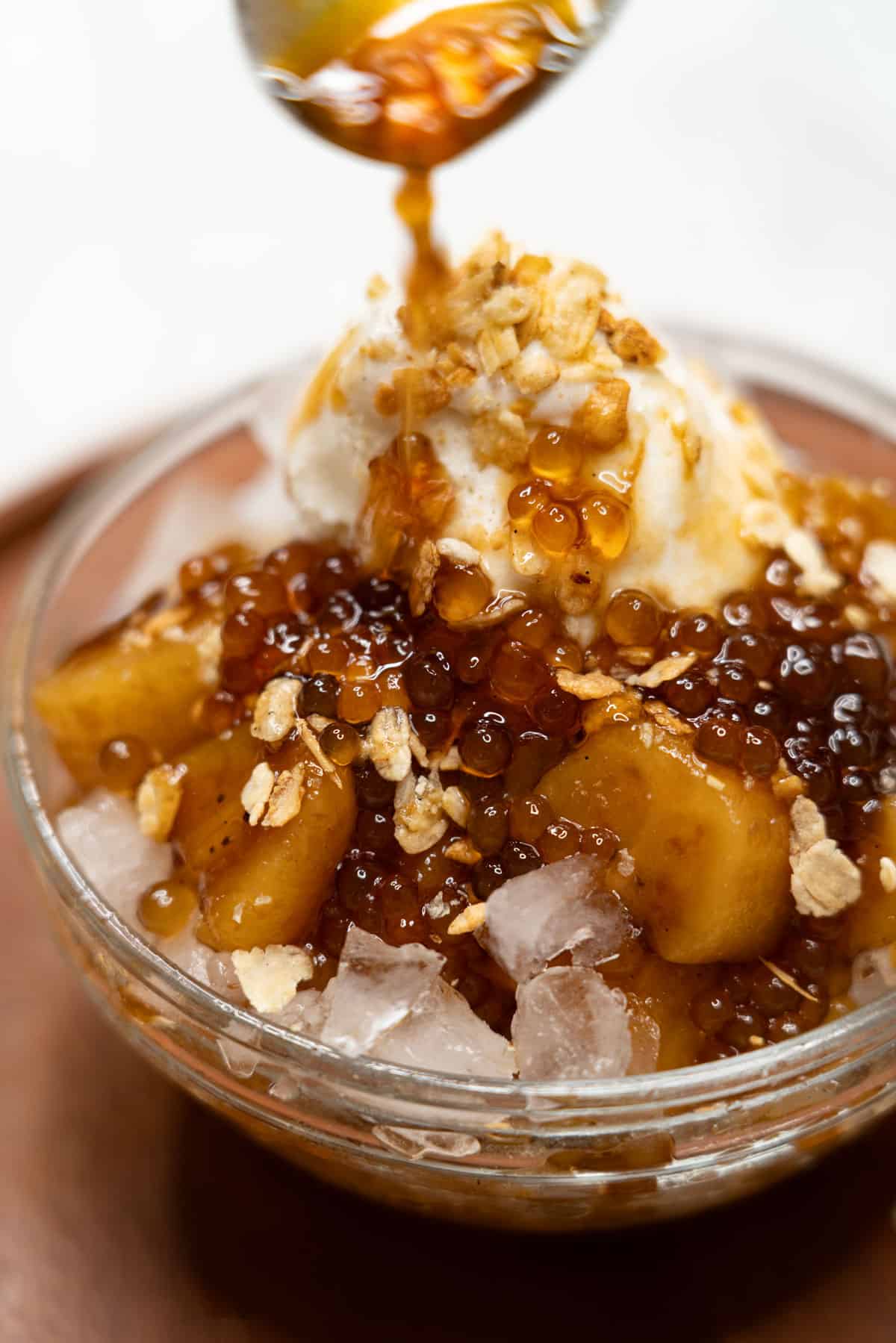 Pouring caramel over saging con yelo (sweetened bananas with ice and milk).