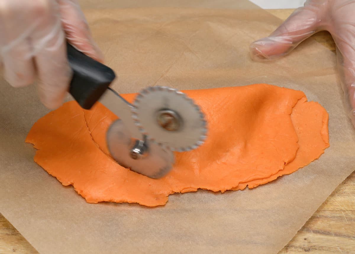 Cutting empanada dough using a pizza cutter.