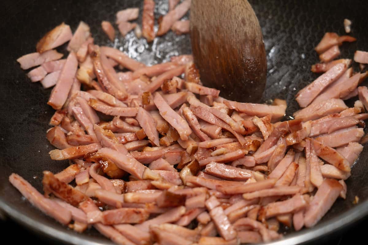 Searing ham slices in a wok.