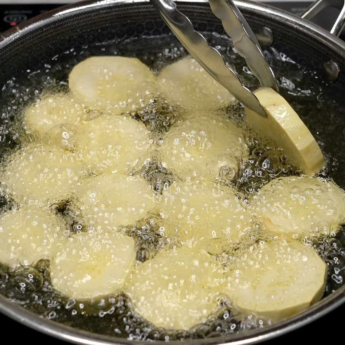 Adding the sweet potatoes to the oil in the pan.