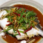 Steamed Pompano Fish with Ginger Scallion Sauce on a plate