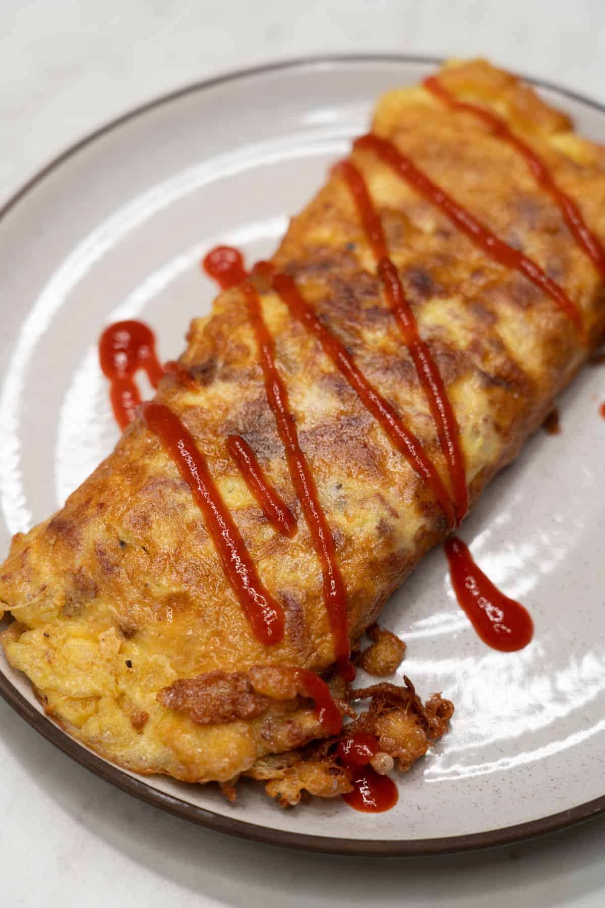 Tortang corned beef with Sriracha on a plate.