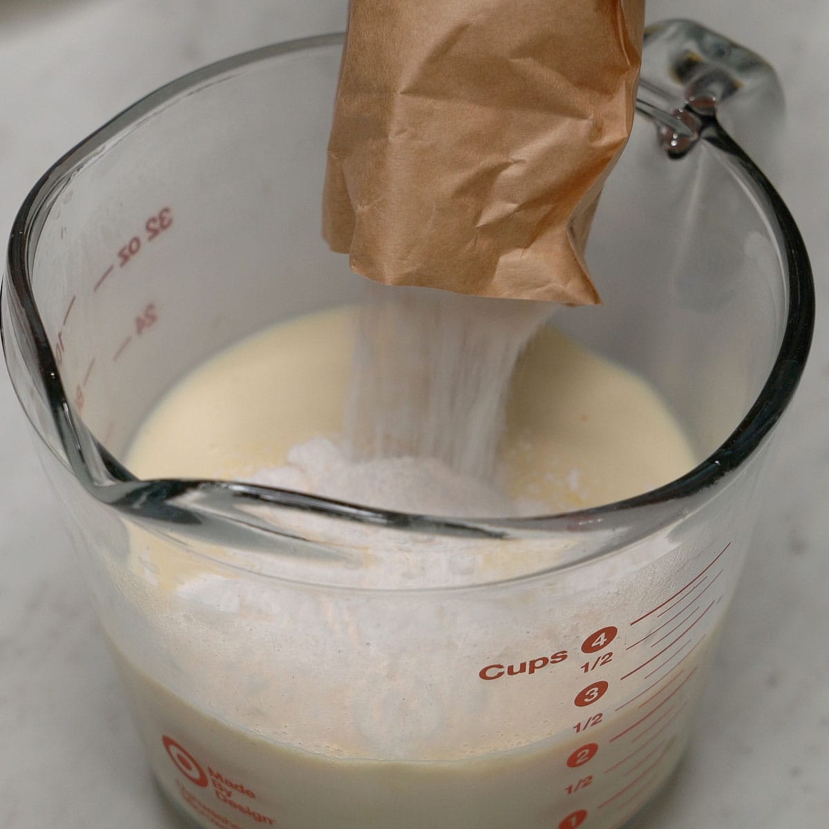 Adding the pudding mix to the liquid in the cup.