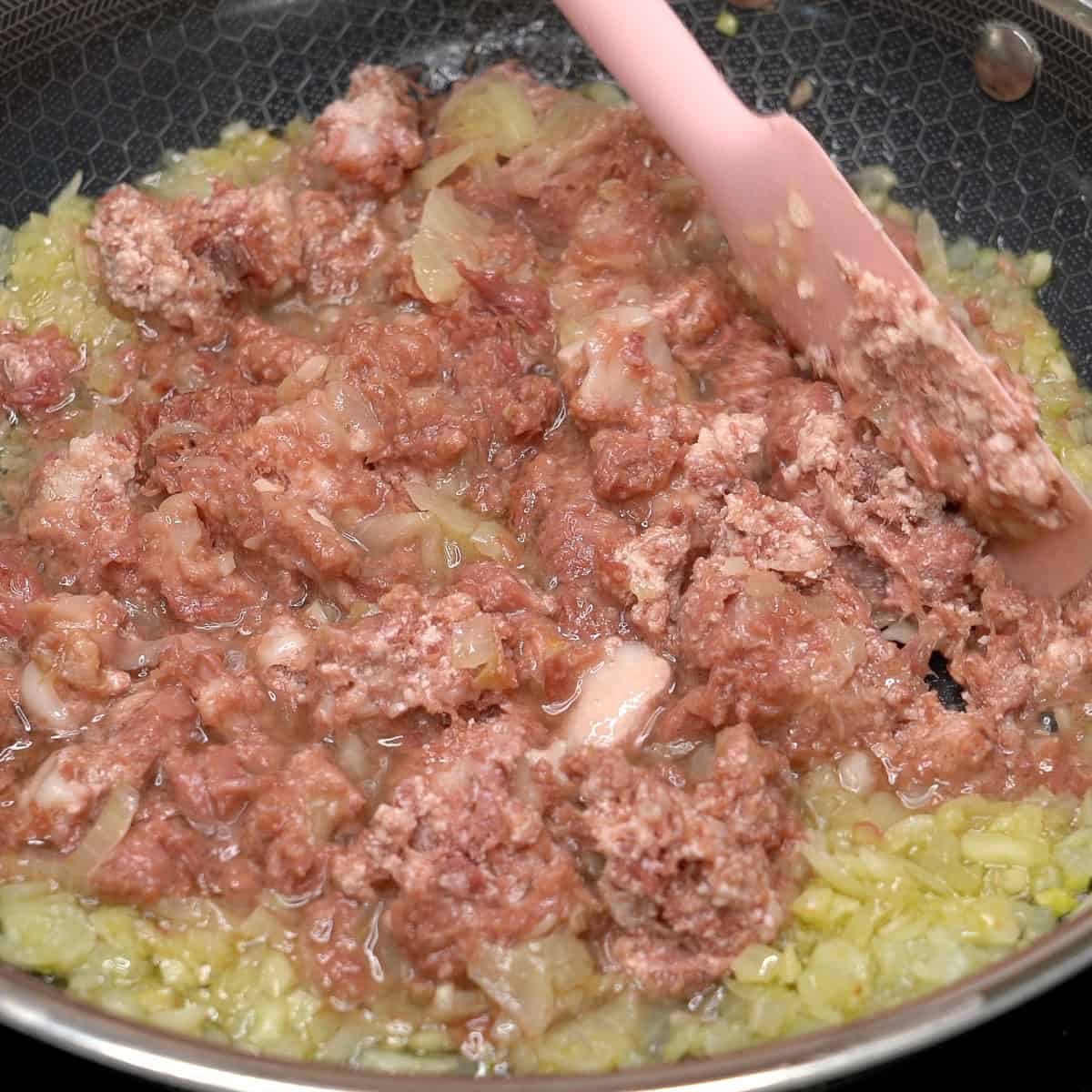 Sauteing the aromatics and corned beef in a pan.