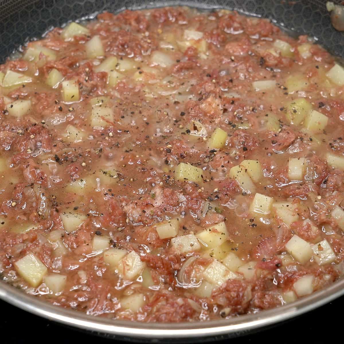 Cooking the corned beef and potatoes in a pan.