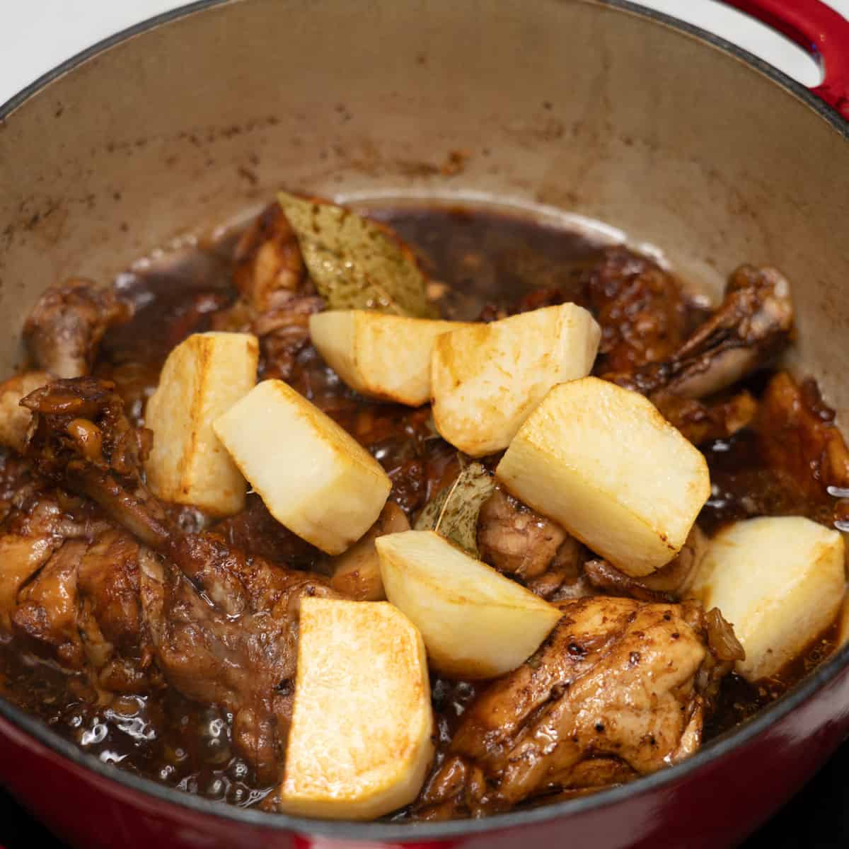 adding potatoes on adobo