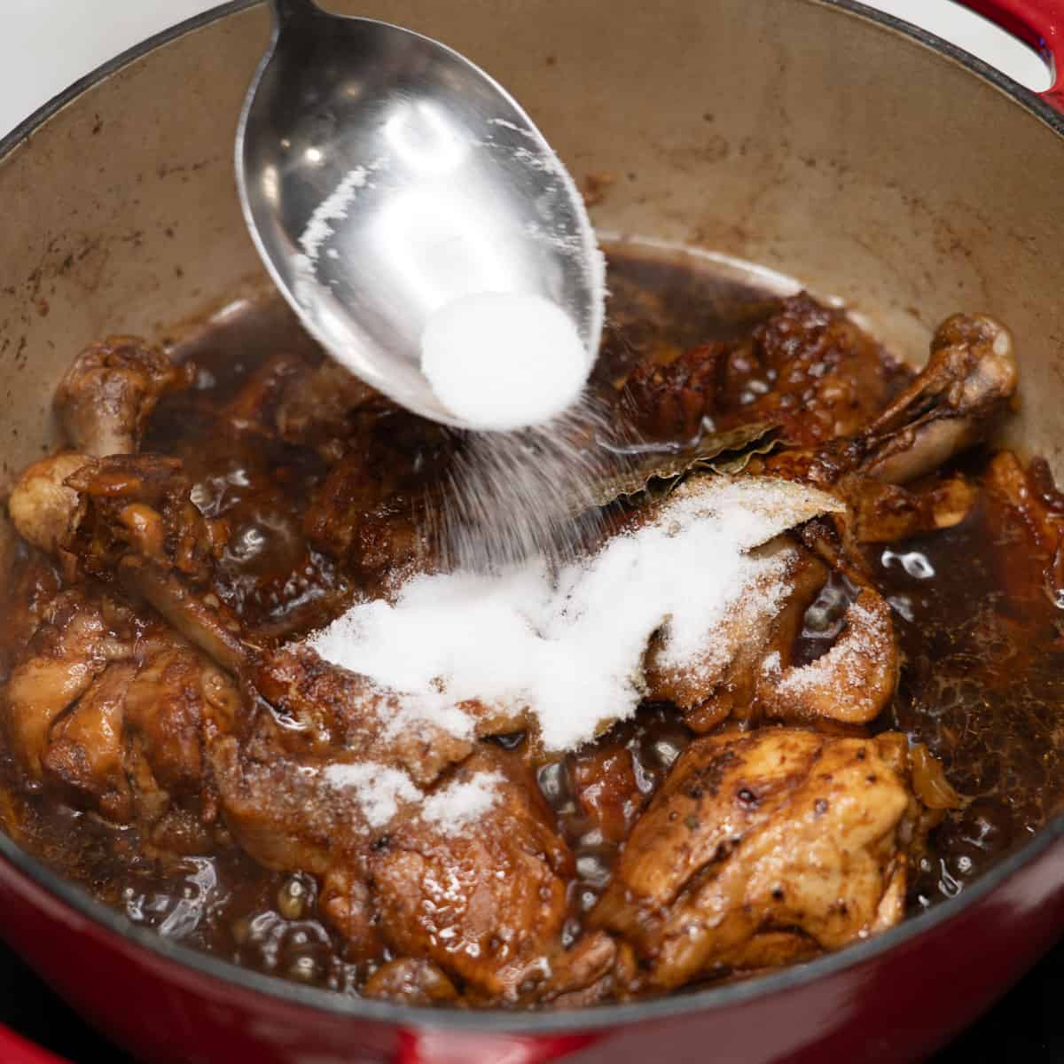 adding sugar on adobo