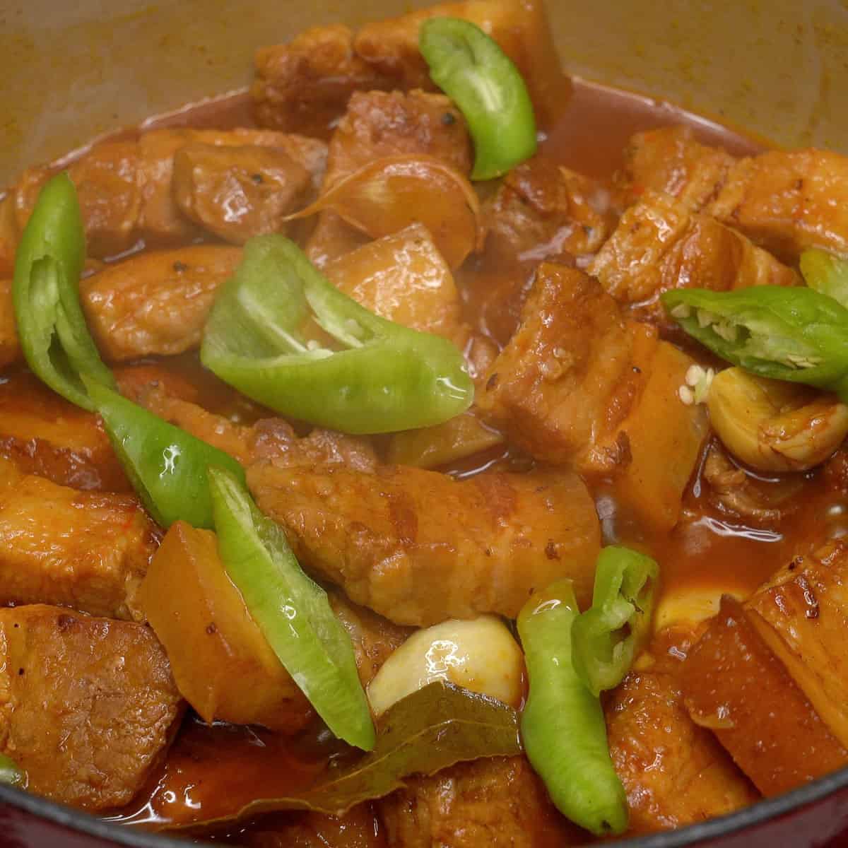 Simmering adobong pula with chilies in a pot.
