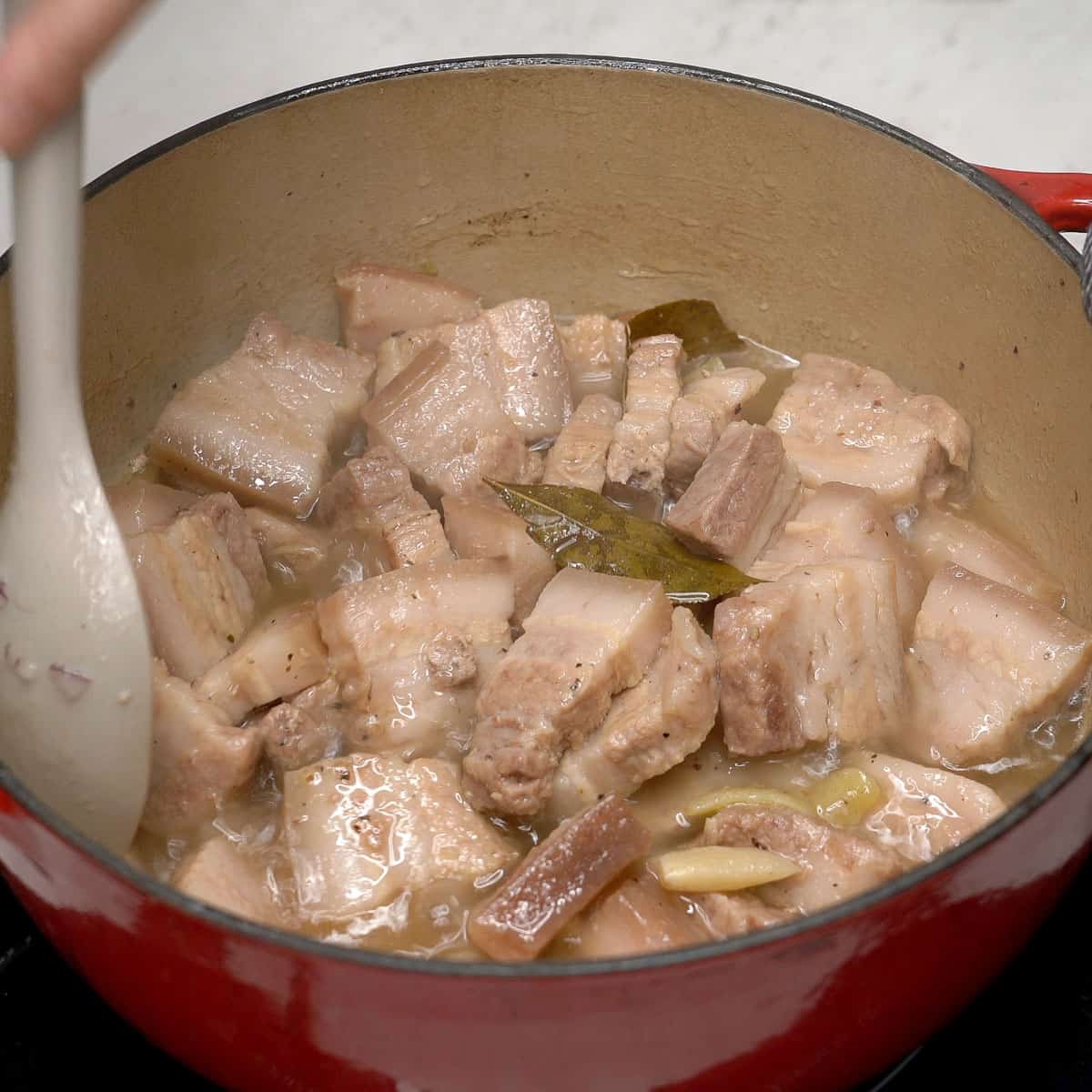 Mixing the adobo sa asin in a pot.