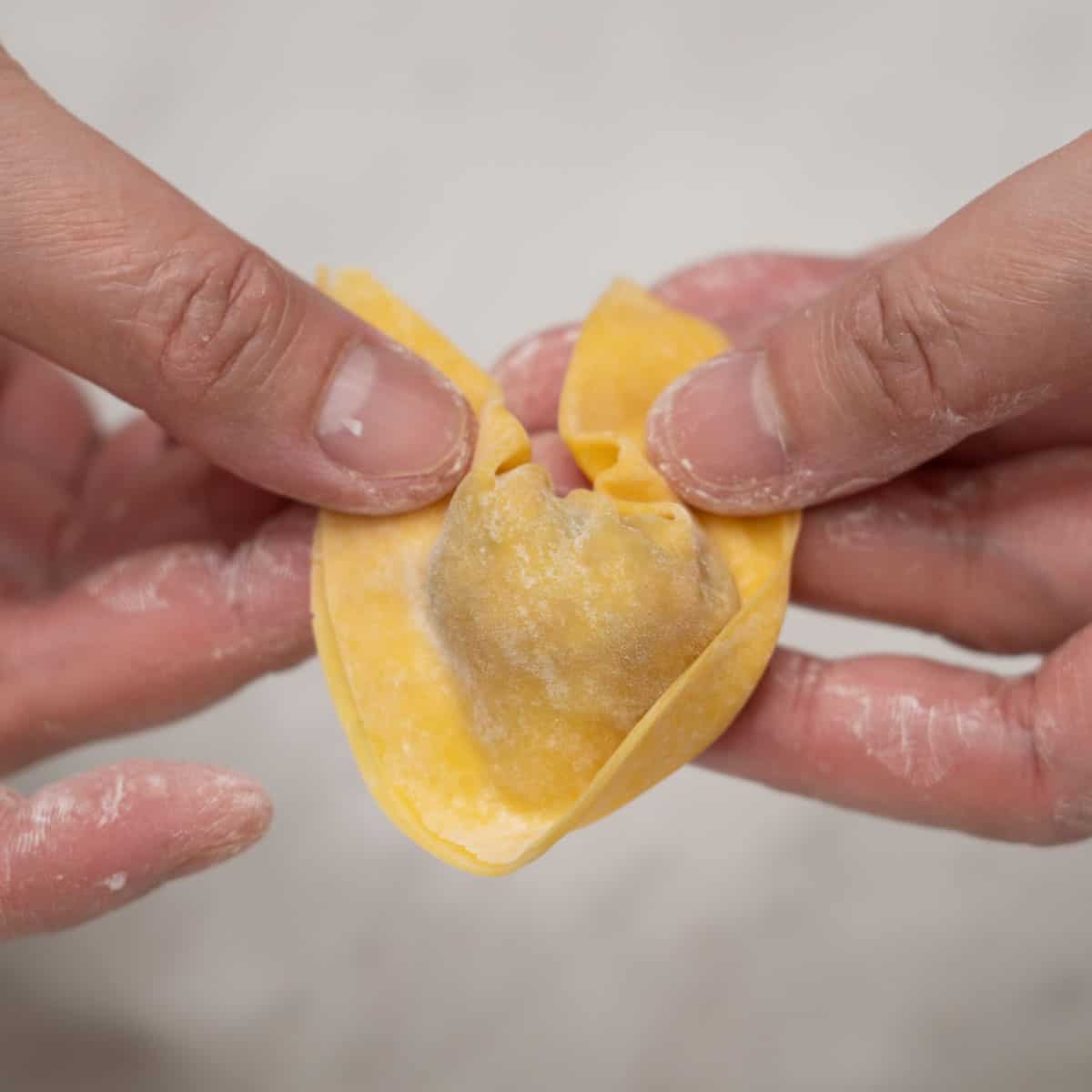 Forming the wonton wrapper into a boat shape.