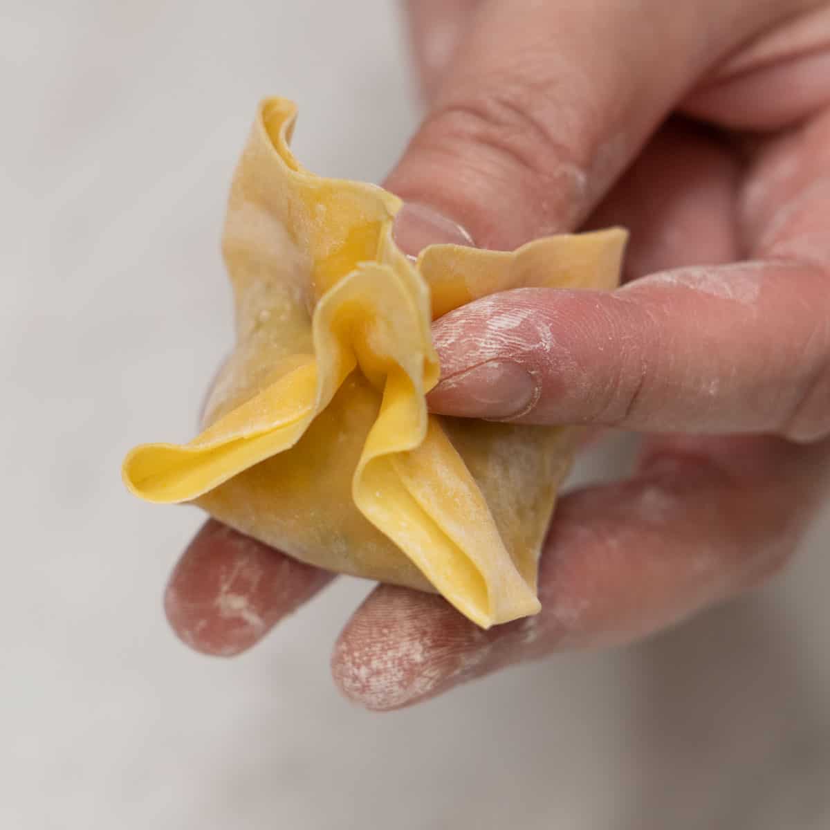 Forming the wonton wrapper into a pyramid fold.