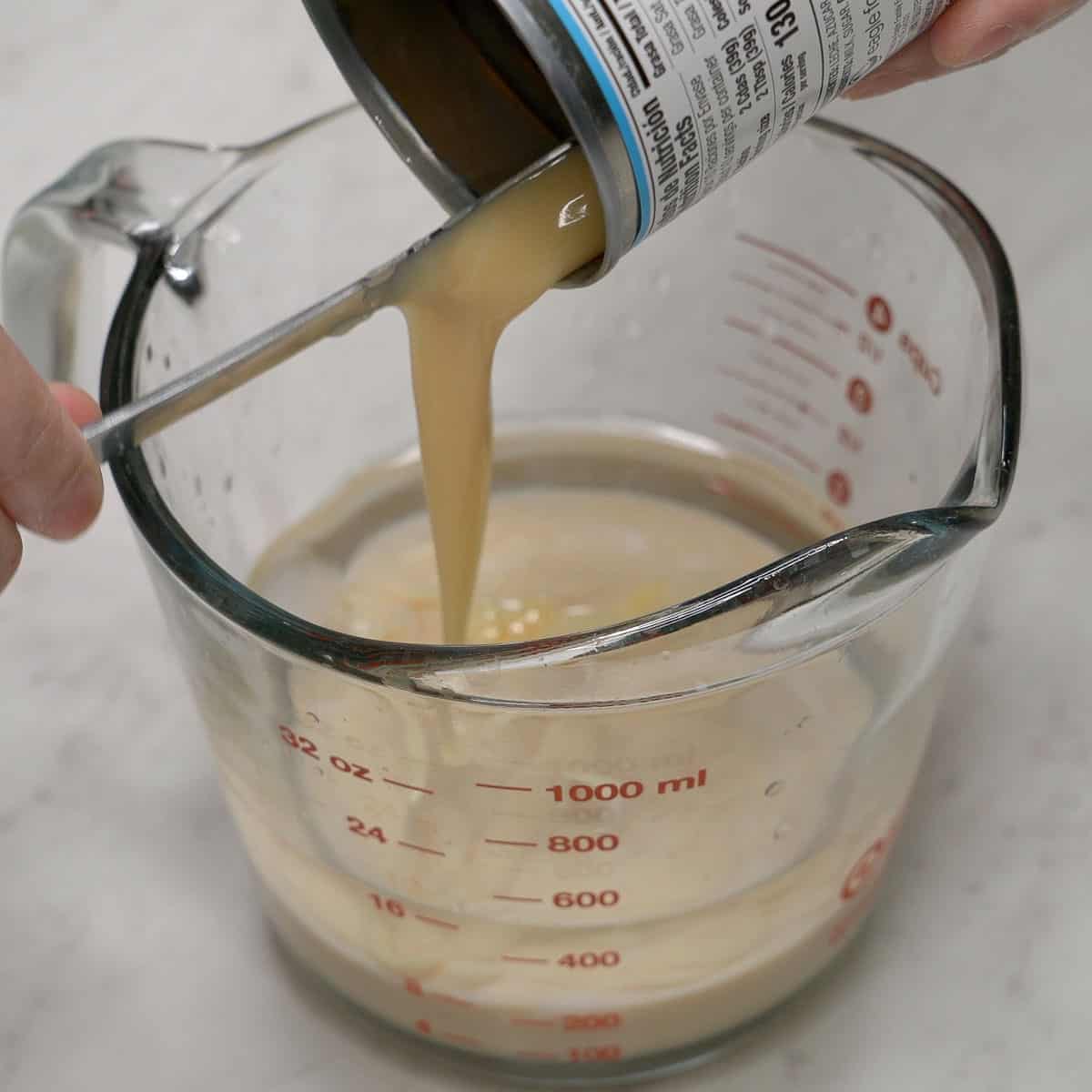 Mixing cold water and condensed milk in a cup.