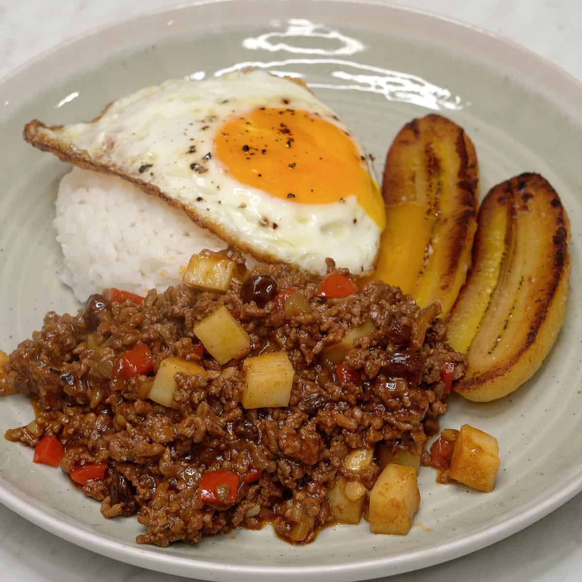 Arroz a la Cubana on a plate with rice, picadillo, fried egg, and saba bananas.