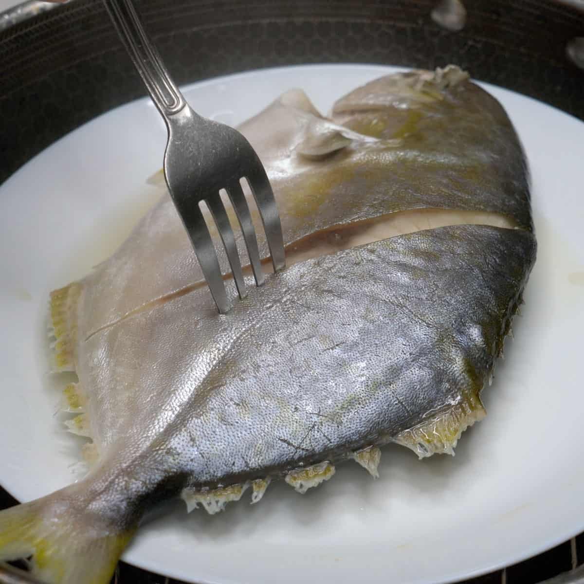 Checking the pompano with a spoon for doneness.