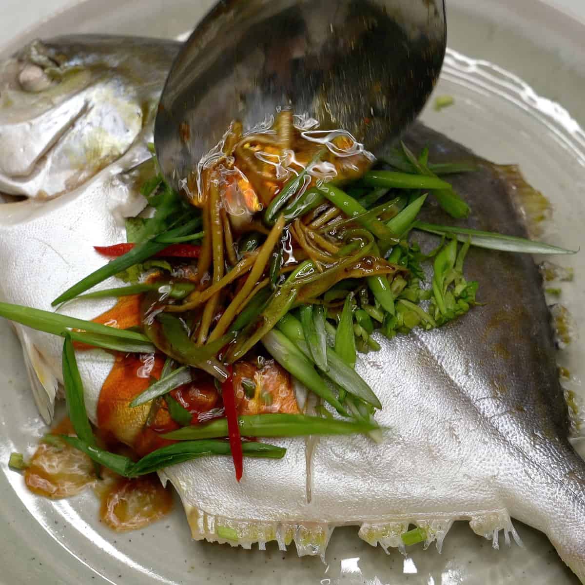 Spooning the hot sauce over the steamed pompano.