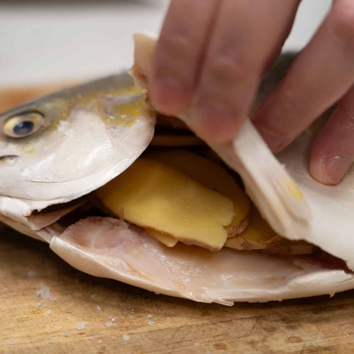Stuffing the fish belly with sliced ginger.