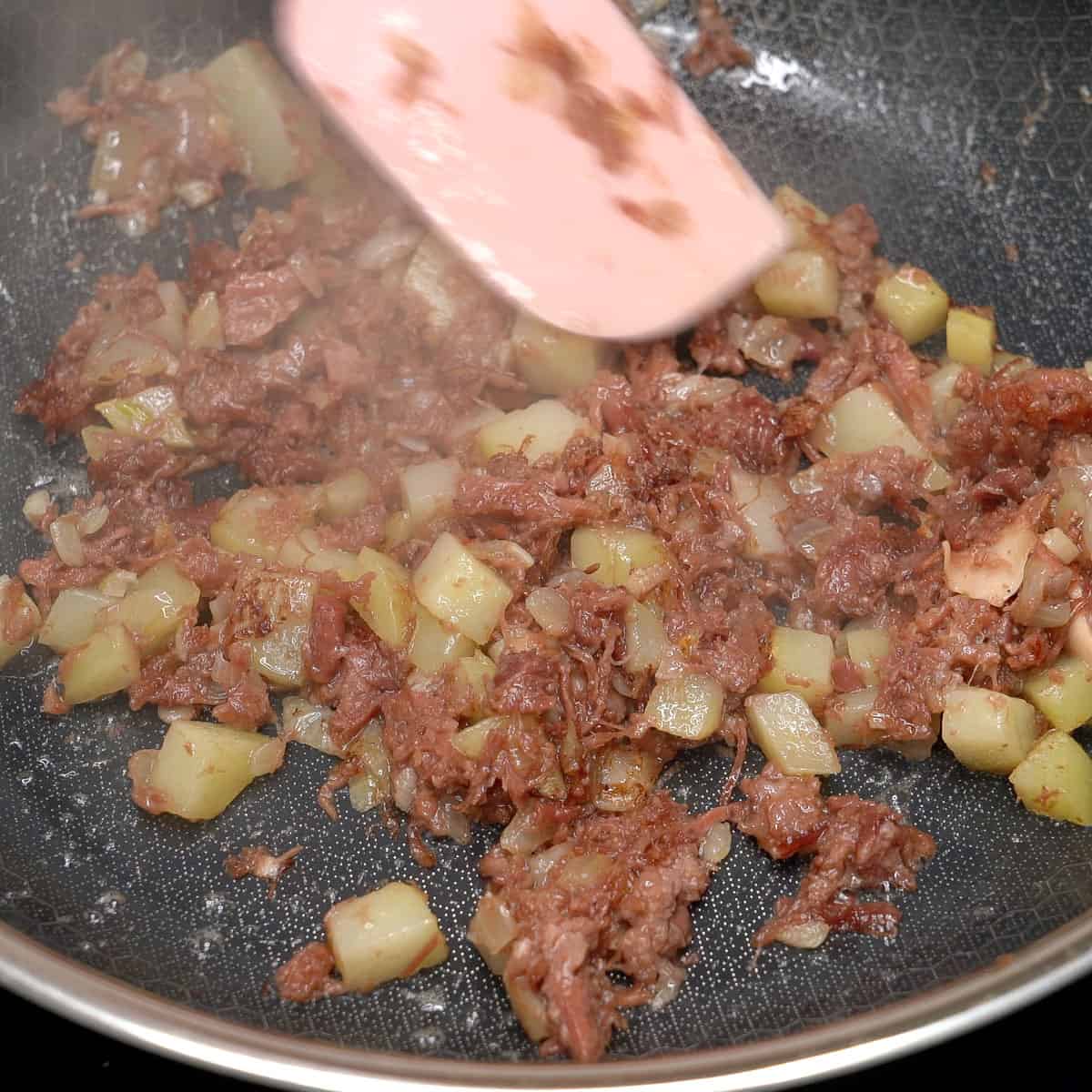 Reheating leftover corned beef in a pan.