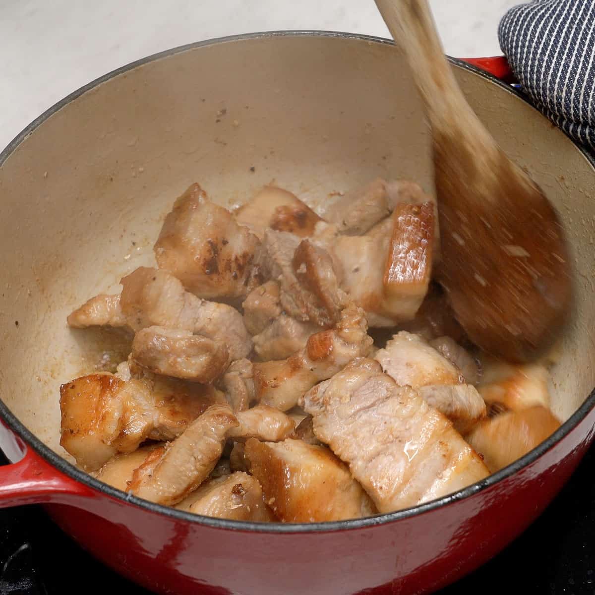 Browning pork in a pot.