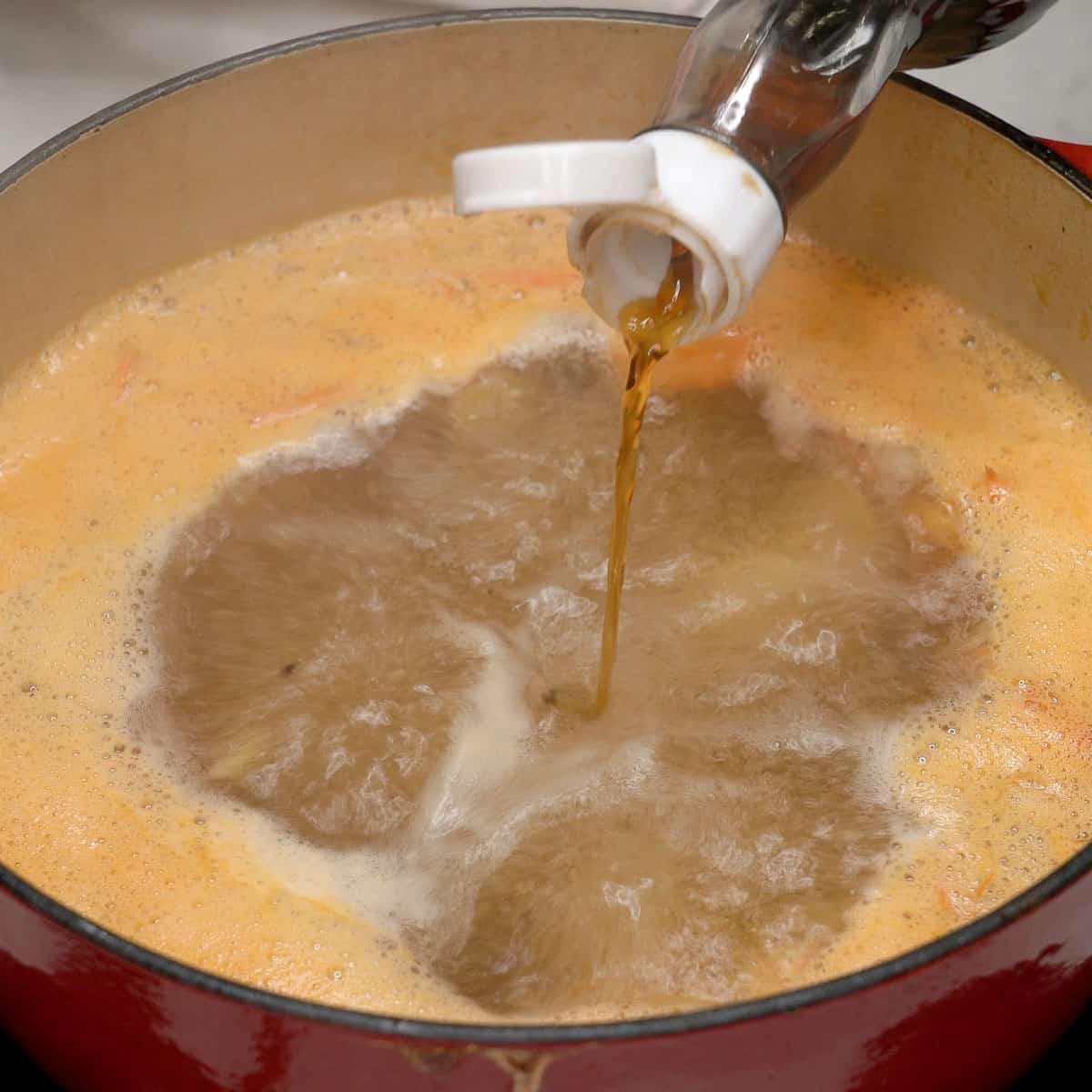 Adding fish sauce to the boiling broth in the pot.