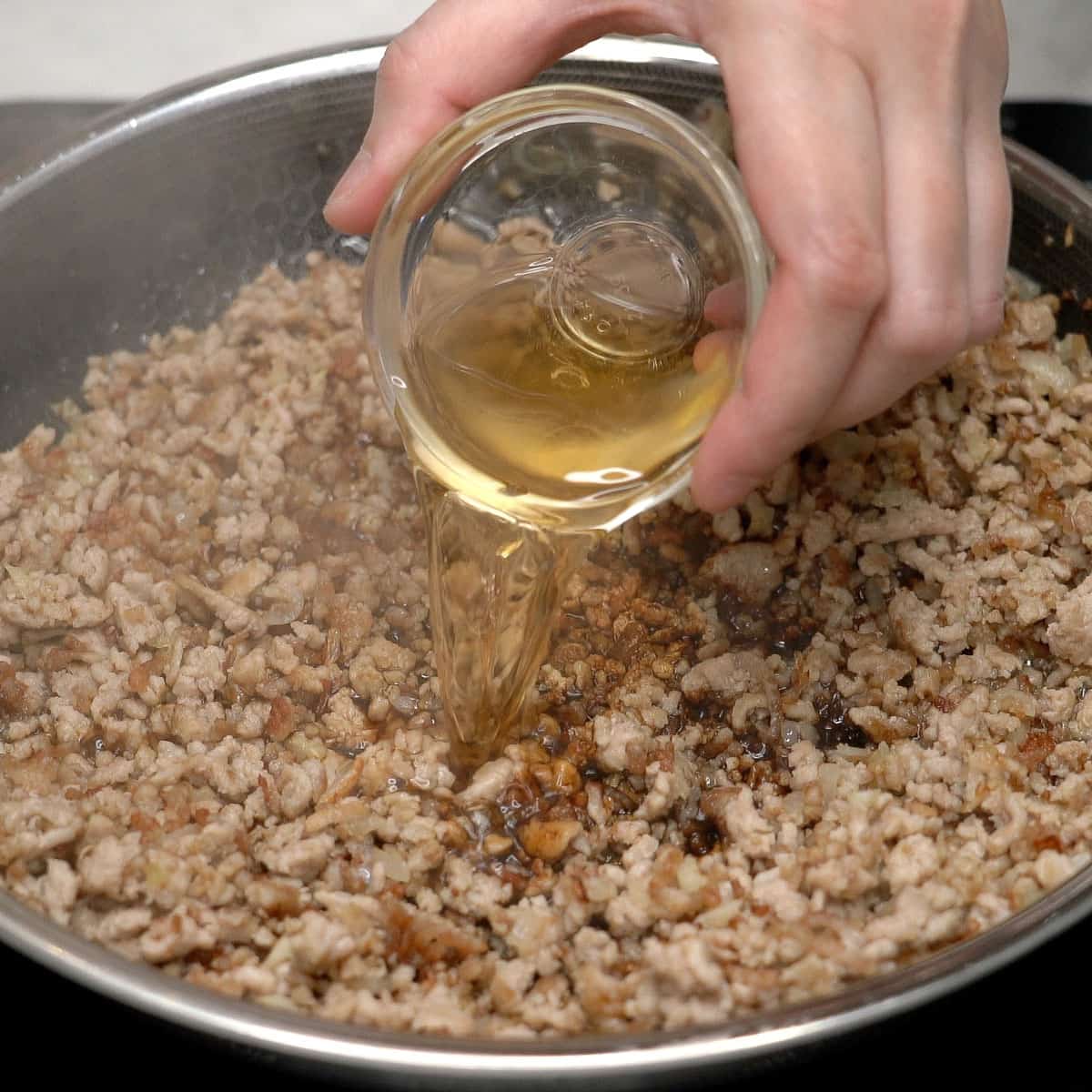 Adding seasonings to the pork in the pan.