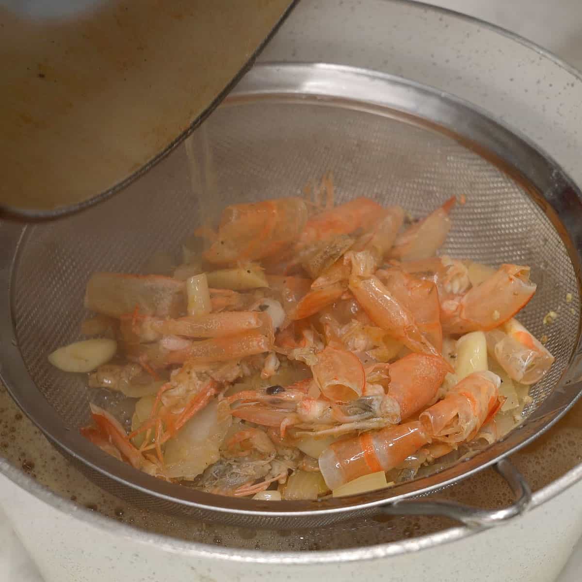 Straining the shrimp broth using a fine strainer.